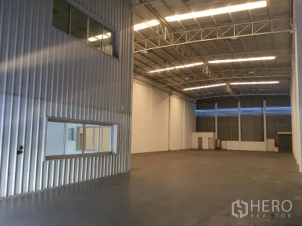 Factory for rent in Khlong Luang, Pathum Thani - High-ceiling warehouse interior with steel trusses, bright strip lighting, smooth floor, and internal windows.