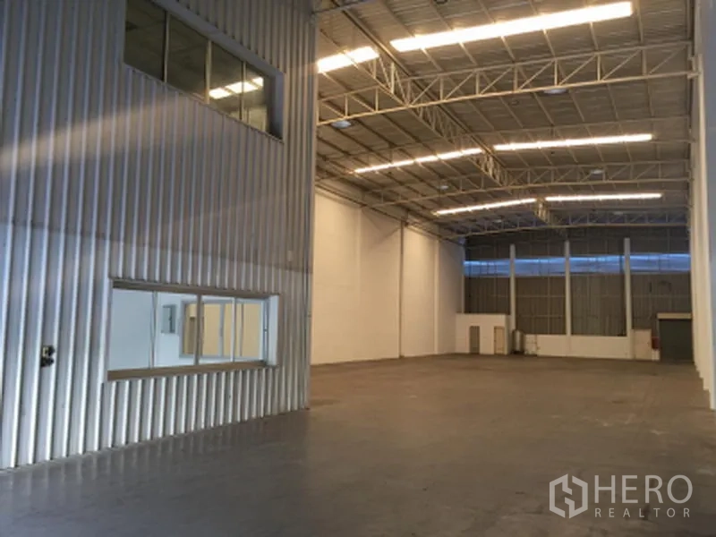 Factory for rent in Khlong Luang, Pathum Thani - High-ceiling warehouse interior with steel trusses, bright strip lighting, smooth floor, and internal windows.