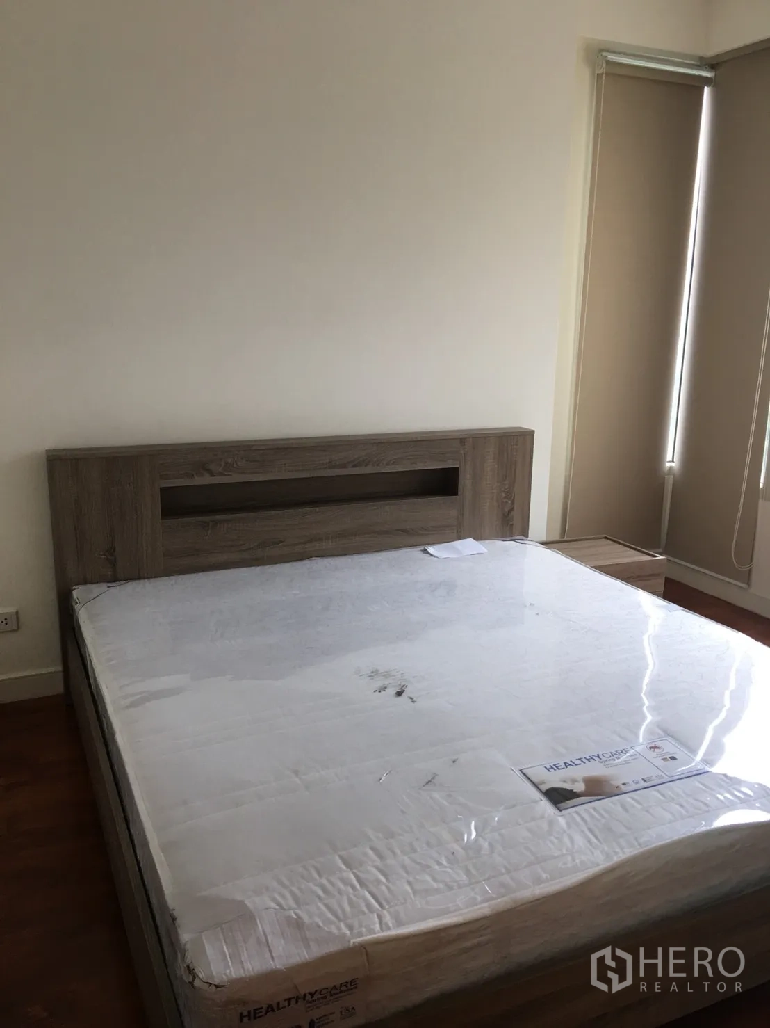 Condominium for rent in Watthana, Bangkok - Bedroom with large bed, wood headboard and blackout blinds.