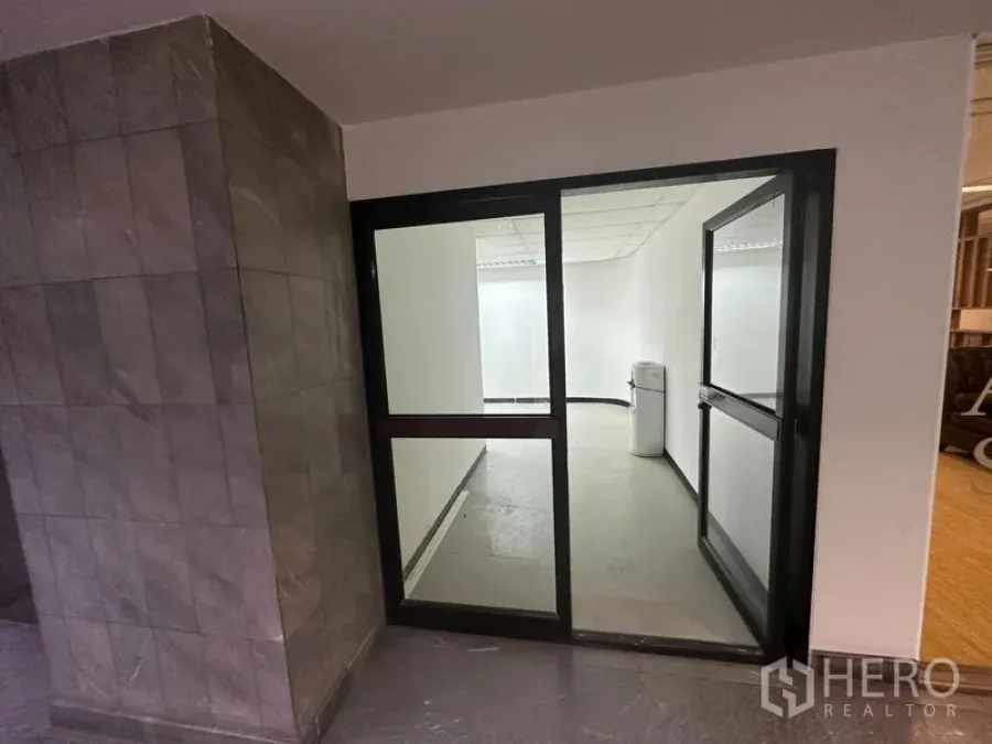 Office Space for rent in Khlong Toei, Bangkok - Glass-door office entrance from the corridor beside tiled walls.