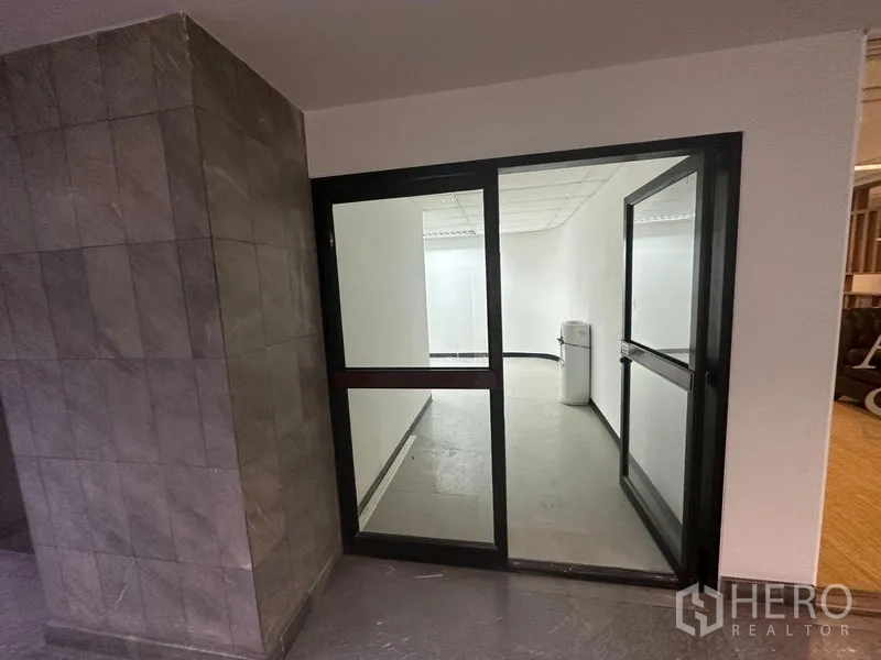 Office Space for rent in Khlong Toei, Bangkok - Glass-door office entrance from the corridor beside tiled walls.