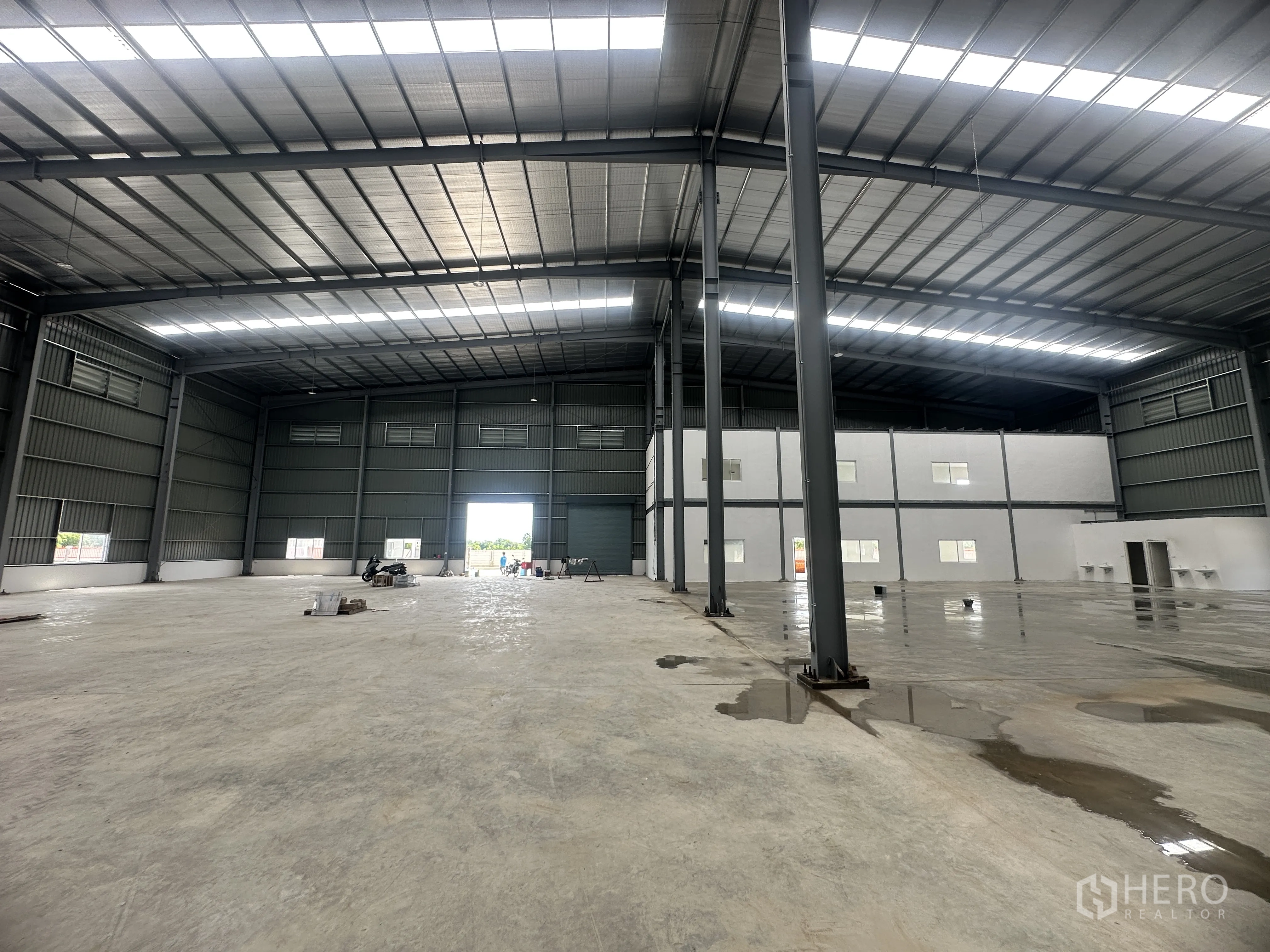 Warehouse for rent or sale in Lam Luk Ka, Pathum Thani - Interior view toward the office block and a wide loading opening with concrete flooring.