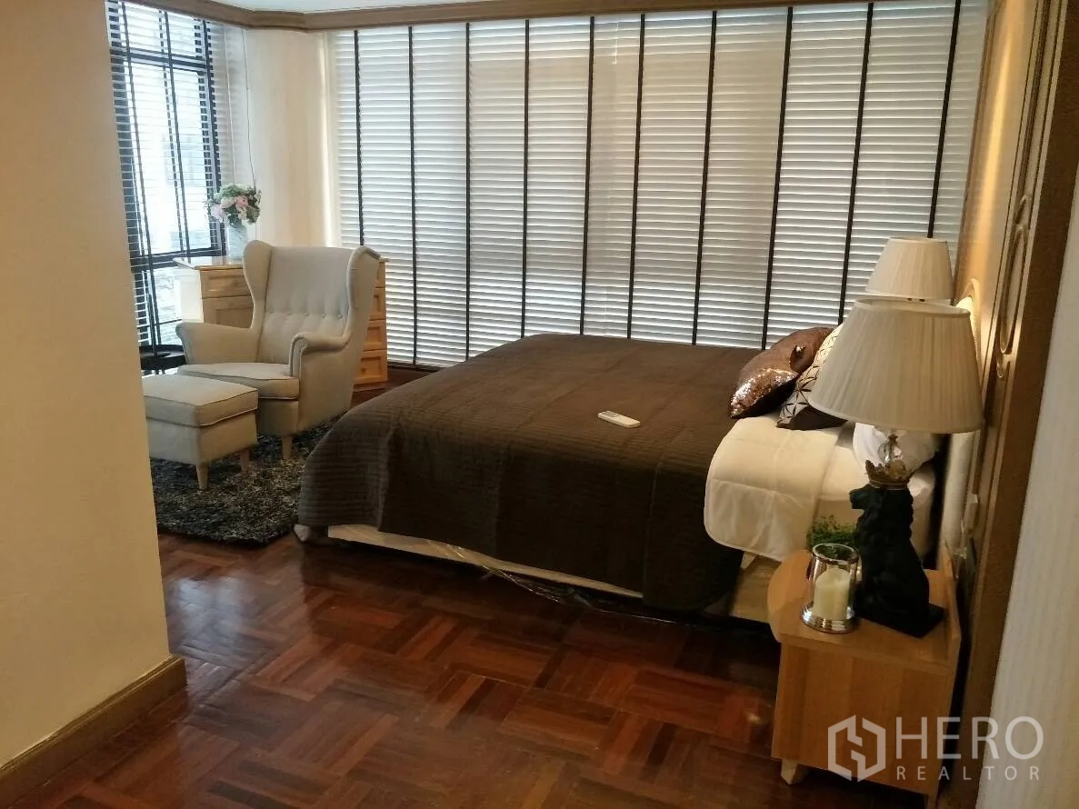 公寓 出租在Watthana, Bangkok - 第二卧室设躺椅与脚凳，落地百叶与温暖木地板。