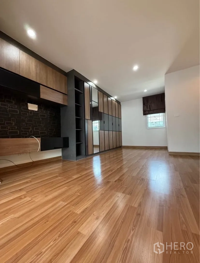 Townhouse for rent in Suan Luang, Bangkok - Primary bedroom with built-in wardrobes, dressing area and wood floors.