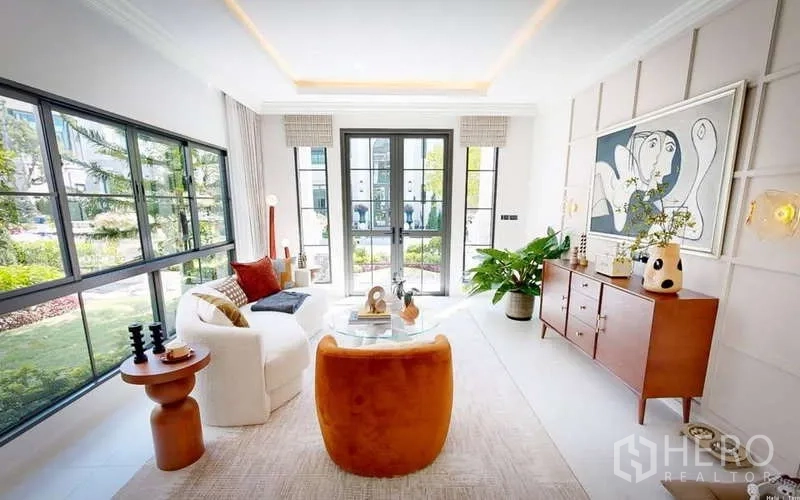 独立式住宅 出租在Bang Phli, Samut Prakan - 舒适客厅，黑框大窗，现代艺术装饰与木质家具，眺望景观花园。