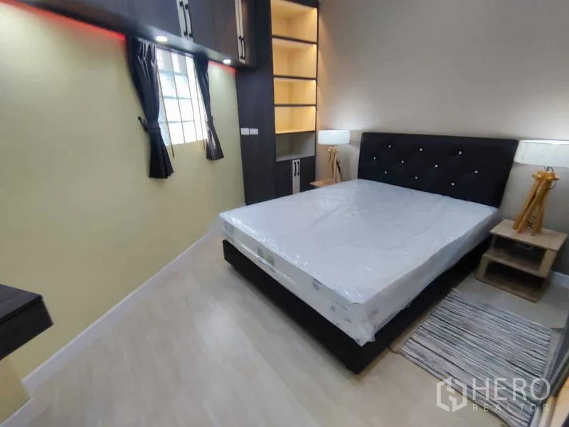 Condominium for rent in Khlong Toei, Bangkok - Master bedroom with upholstered headboard, bedside lamps and illuminated storage shelves.