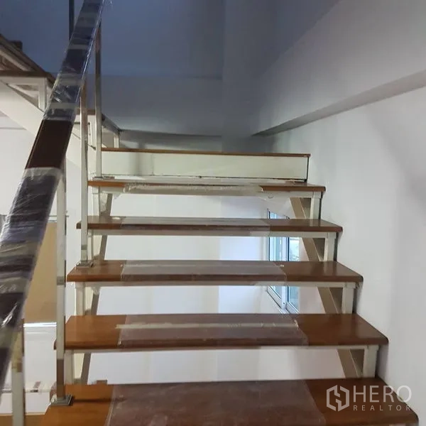 Home Office for sale in Lat Phrao, Bangkok - Staircase with wooden treads and metal handrail connecting office levels.