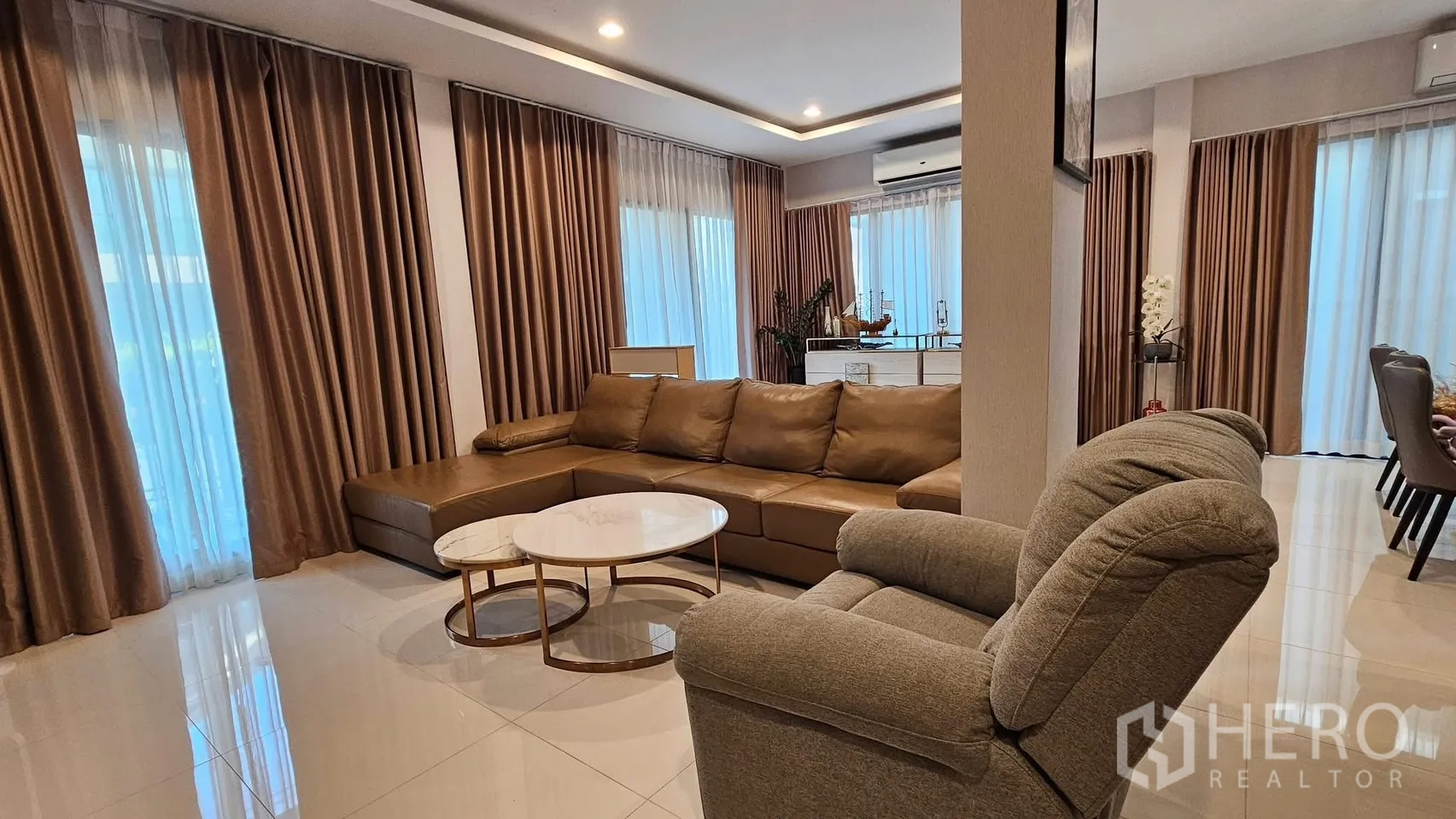 Detached House for rent in Saphan Sung, Bangkok - Wide living-dining space with L-shaped sofa and armchair by tall windows.