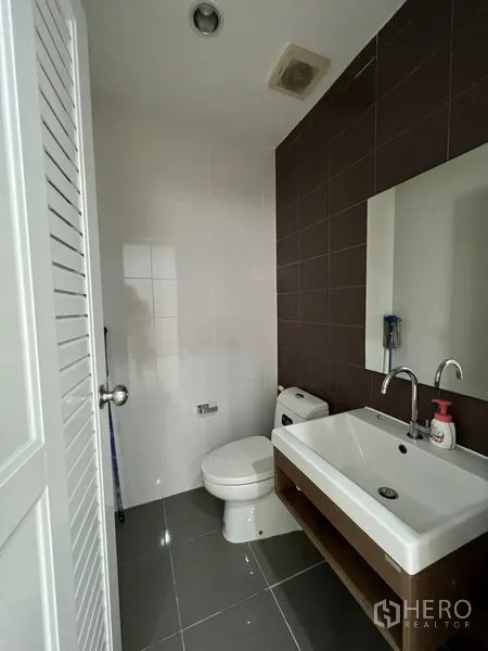 Townhouse for sale in Bang Kapi, Bangkok - Guest bathroom with modern sink, mirror and toilet.