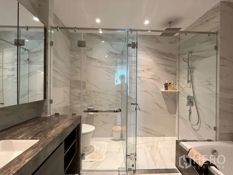 Condominium for rent or sale in Sathon, Bangkok - Expansive bathroom with dual glass showers, rain head and marble tiles.