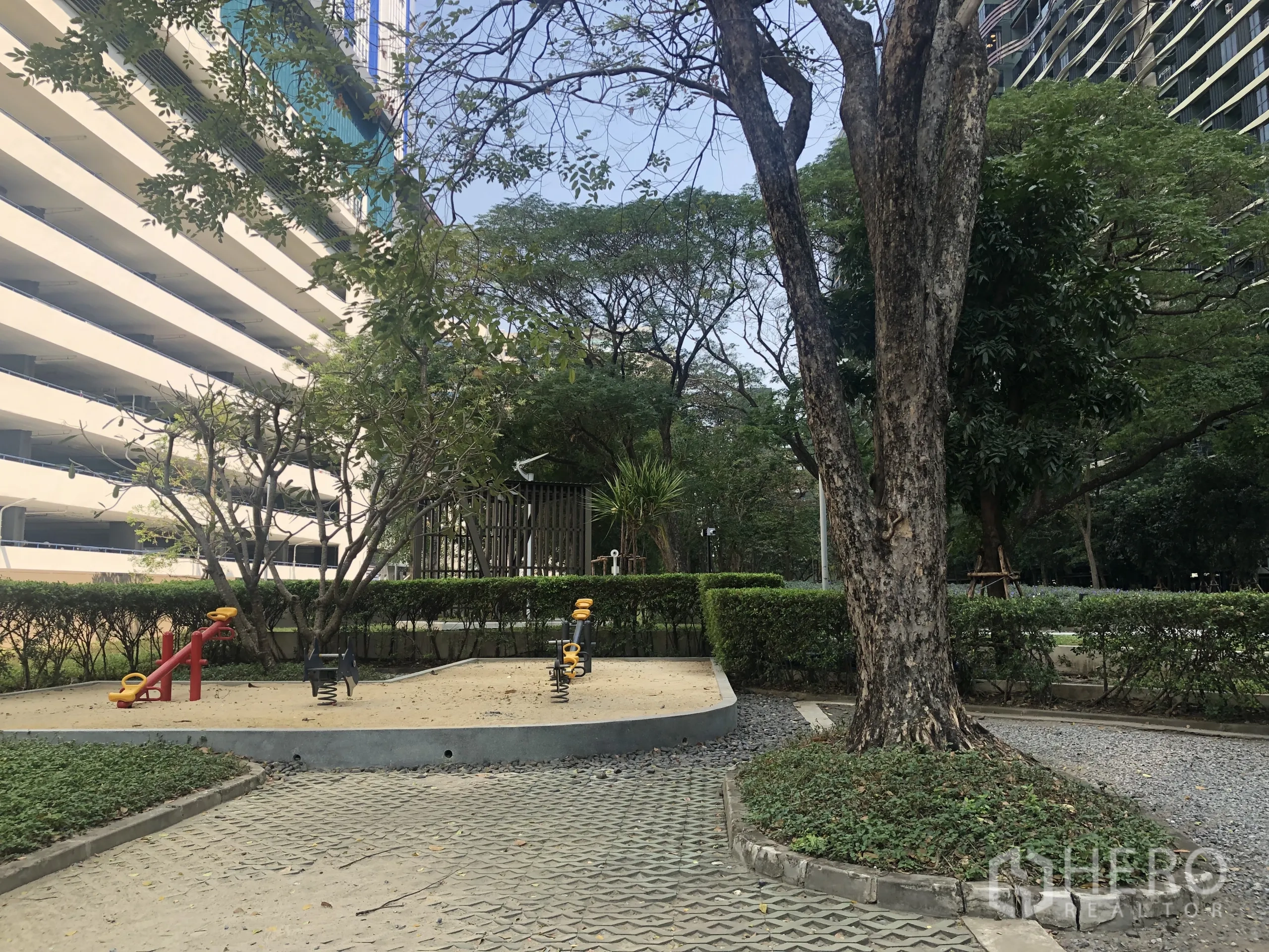 คอนโด ขายในChatuchak, Bangkok - สนามเด็กเล่นพร้อมม้ากระดกสปริงท่ามกลางต้นไม้และพุ่มไม้ในพื้นที่คอนโด