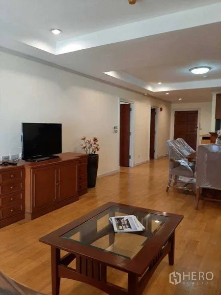 Apartment for rent in Watthana, Bangkok - Living room with TV cabinet and glass coffee table adjoining the dining area and balcony.