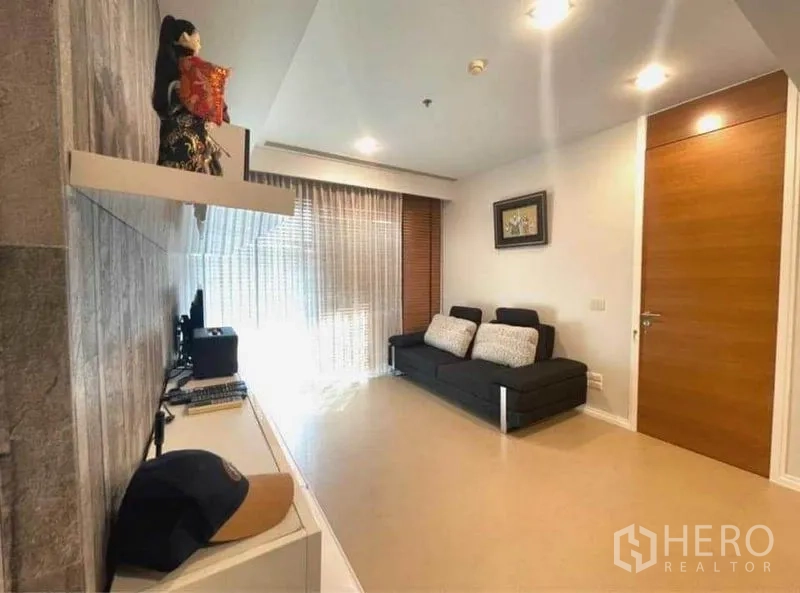 Condominium for rent in Khlong San, Bangkok - Cozy living room with sofa, built‑in desk, large window and sheer curtains.
