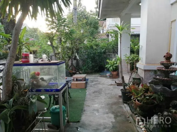 独立式住宅 出售在Prawet, Bangkok - 房屋侧院露台，盆栽、水景与混凝土步道。
