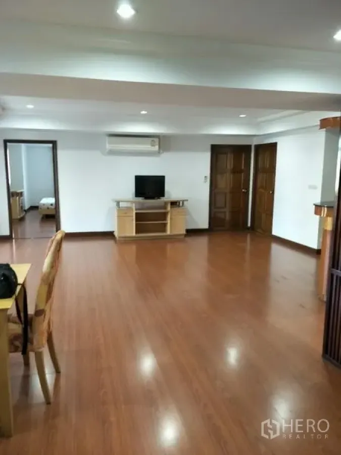 公寓 出租在Watthana, Bangkok - 宽阔起居区配电视柜、空调与通往卧室的多扇门。