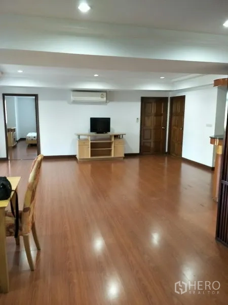 公寓 出租在Watthana, Bangkok - 宽阔起居区配电视柜、空调与通往卧室的多扇门。