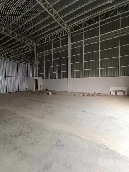 Warehouse for rent in Khlong Toei, Bangkok - Spacious open-plan warehouse hall with steel roof trusses, concrete floor and a small utility room.