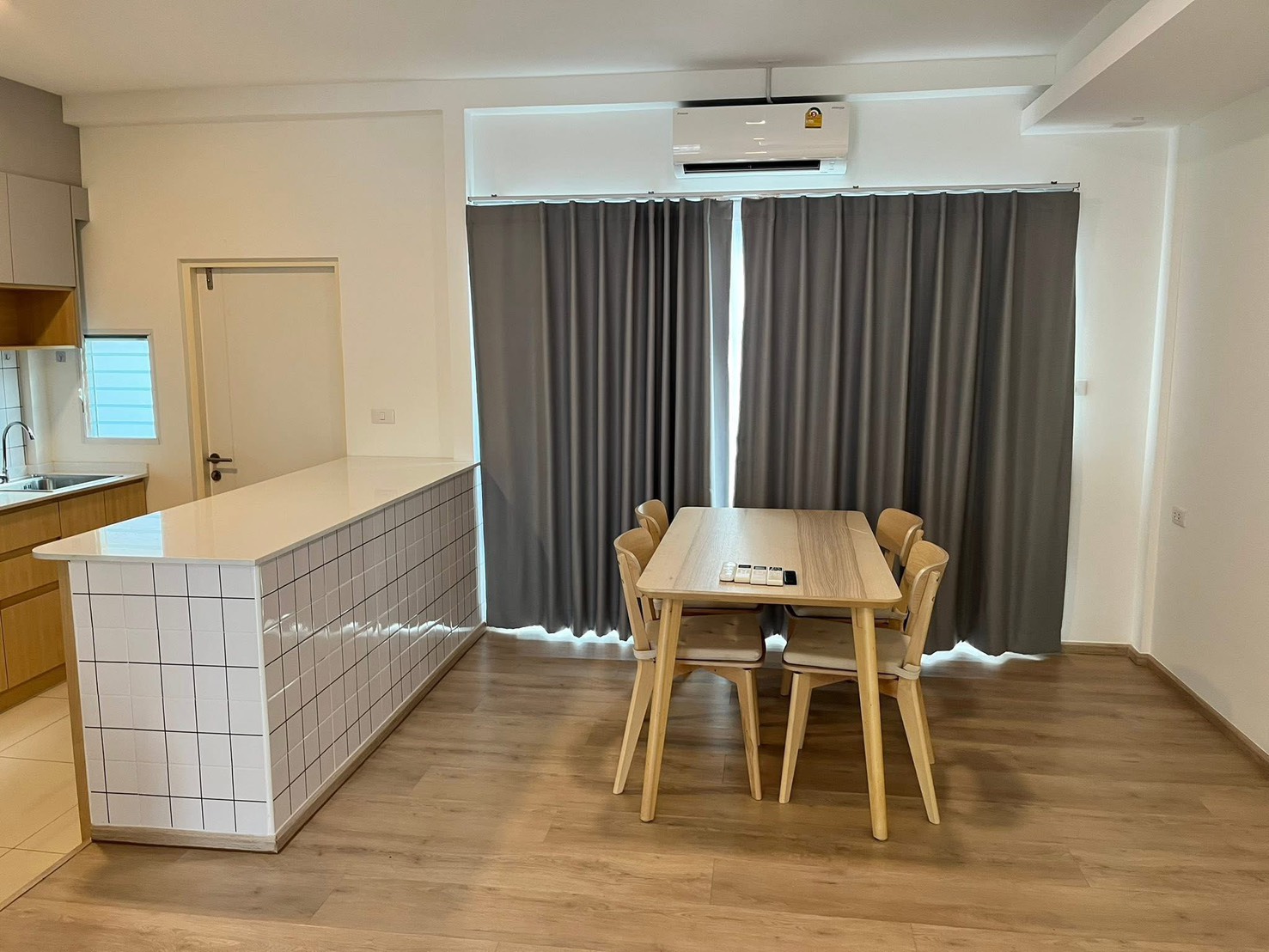 联排别墅 for rent in Prawet, Bangkok - 用餐区，木质餐桌椅，旁有大面积窗帘与空调。