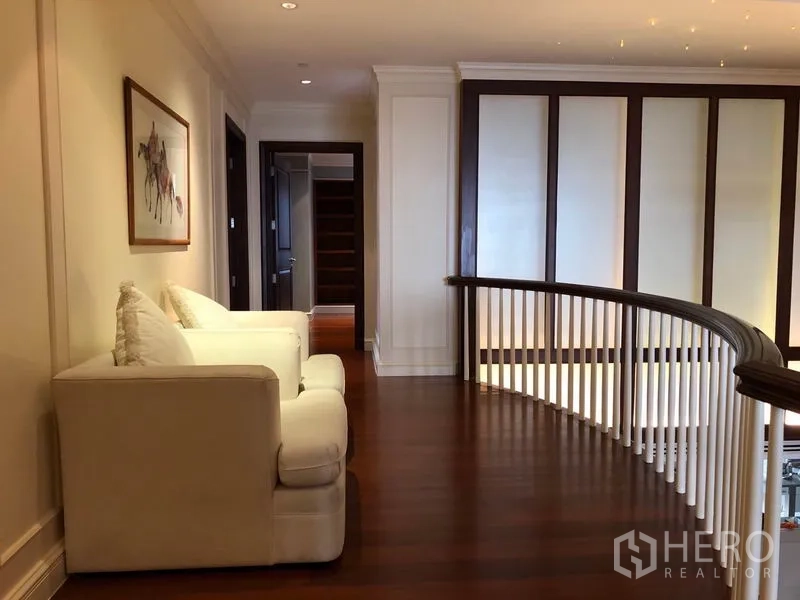 Condominium for rent or sale in Watthana, Bangkok - Upstairs landing with white sofas and a curved balustrade overlooking the living area.