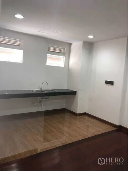 店屋 出租在Bang Rak, Bangkok - 小型茶水间，带水槽与台面，木纹地面与顶灯。