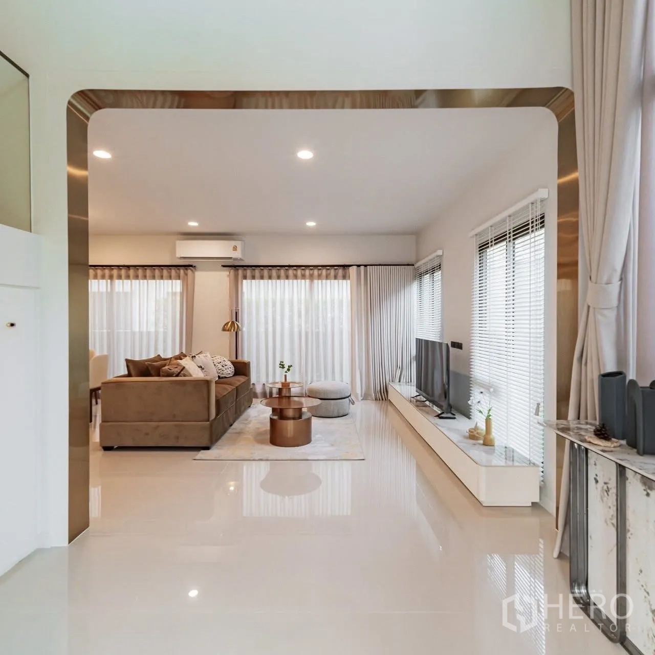 独立式住宅 for sale in Bang Kapi, Bangkok - 开放式客厅，转角沙发、电视柜、落地窗与亮面地砖，现代感十足。
