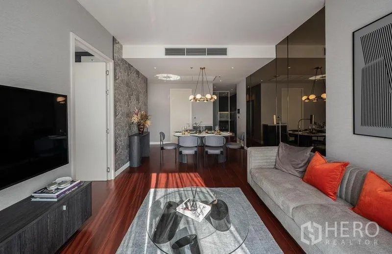 Condominium for rent in Watthana, Bangkok - Bright living and dining area with modern chandelier, gray sofa, wall-mounted TV and warm wood floors in a Watthana, Bangkok condo.