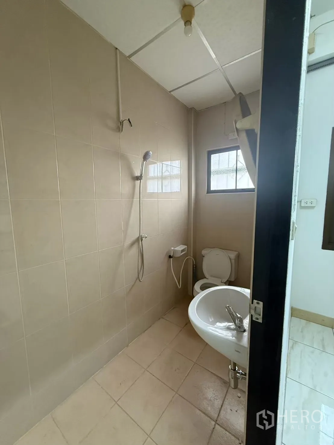 Shophouse for rent in Pak Kret, Nonthaburi - Bathroom with shower, toilet, and sink with a small window.