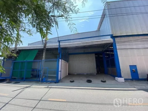 Factory for rent or sale in Bang Sao Thong, Samut Prakan - Street view of a metal-clad factory exterior with wide roller shutter and covered loading bay in Bang Sao Thong.