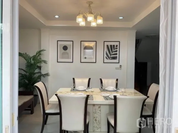 独立式住宅 出租在Suan Luang, Bangkok - 餐厅设六人石面餐桌、吊灯和装饰画。