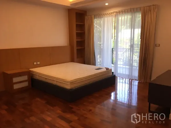 บ้าน ให้เช่าในWatthana, Bangkok - ห้องนอนสว่างพื้นไม้ พร้อมชั้นบิลต์อิน และประตูกระจกบานเลื่อนออกสู่ระเบียง.
