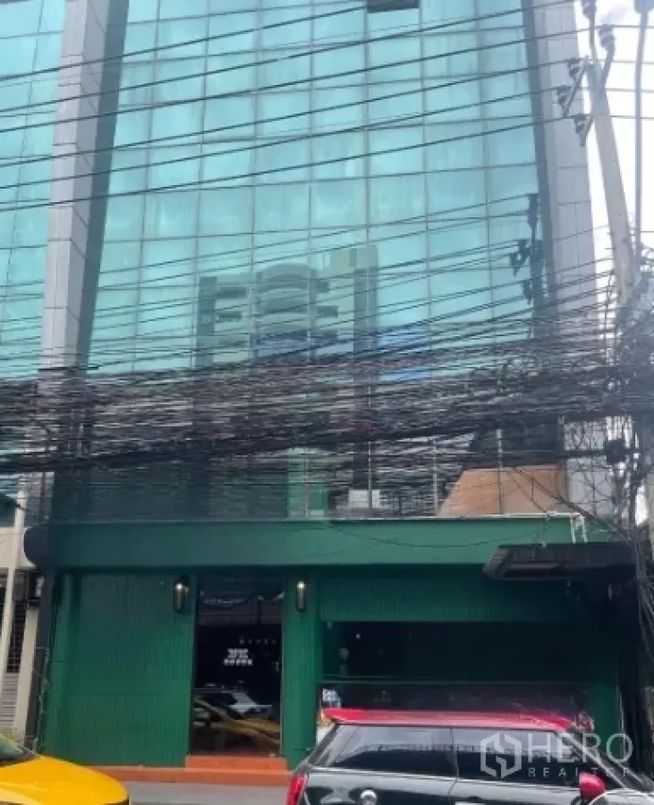 店屋 出租在Watthana, Bangkok - 通罗街区玻璃外立面建筑，底层绿色商铺临街。