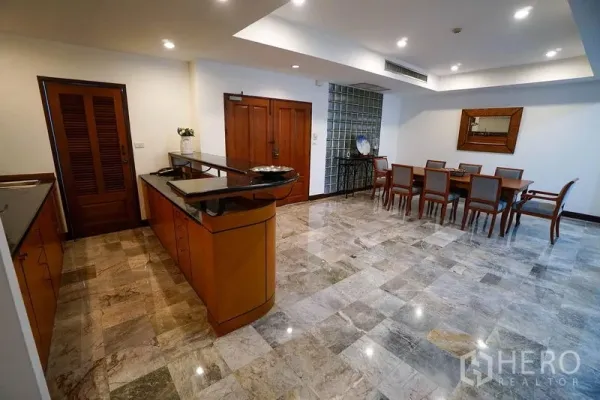Apartment for rent in Watthana, Bangkok - Open kitchen featuring a long island, stone countertops and views toward the dining area on polished marble flooring.