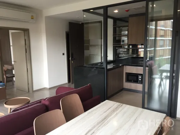 公寓 出租在Watthana, Bangkok - 开放式起居区，带大理石餐桌与玻璃隔断的L形厨房，木质橱柜与嵌入式微波炉。