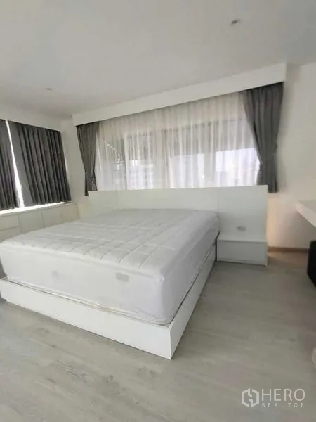 公寓 出租在Bang Rak, Bangkok - 温馨卧室，大窗配双层窗帘，白色床与床头柜。