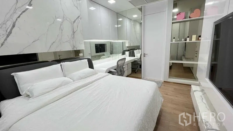 Condominium for rent in Watthana, Bangkok - Primary bedroom with king bed, mirrored wardrobe and long study desk.