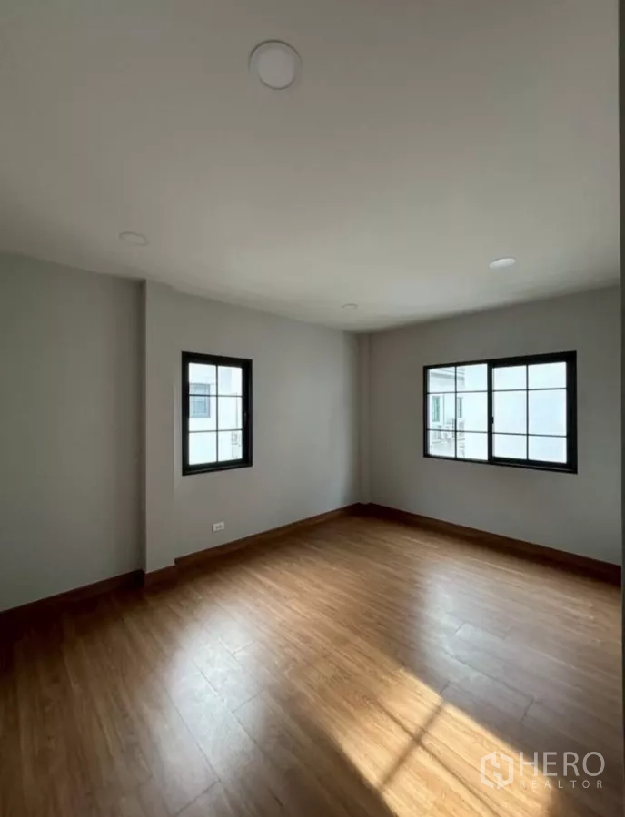 Detached House for rent in Bang Phli, Samut Prakan - Sunlit corner bedroom with wood floors and two windows.