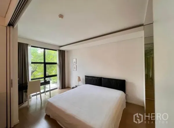 Condominium for rent in Watthana, Bangkok - Spacious bedroom with king bed, desk by the window, and light wood flooring.