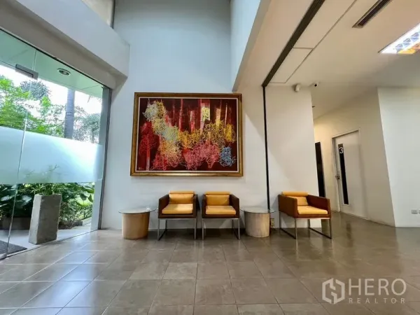 Office Space for rent in Bueng Kum, Bangkok - Modern lobby with high ceiling, large abstract artwork, armchairs, and a glass entrance revealing landscaped gardens.