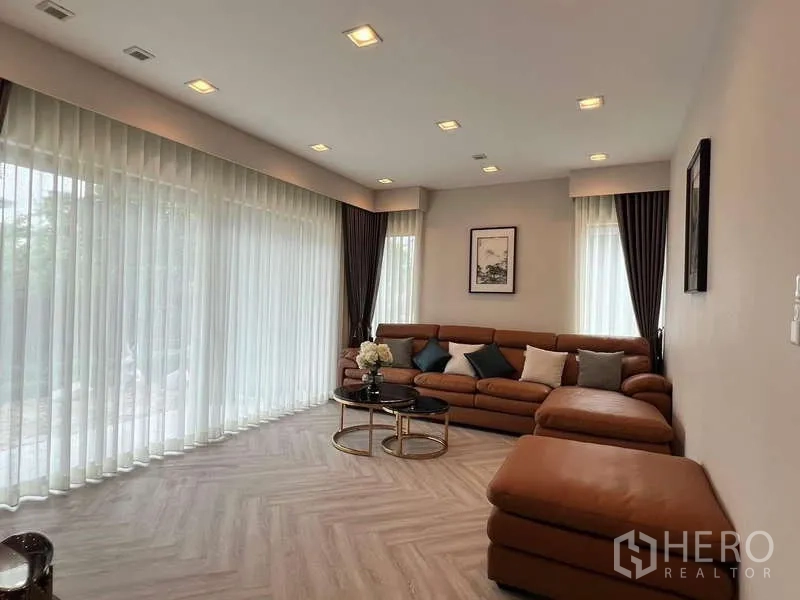 独立式住宅 出租或出售在Lat Krabang, Bangkok - 客厅落地纱帘环绕，大型L形沙发。