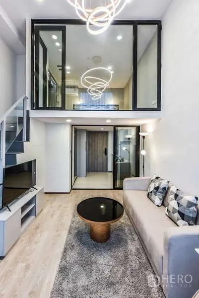 Condominium for rent in Huai Khwang, Bangkok - View of mezzanine above living room with designer lighting and glass panels.