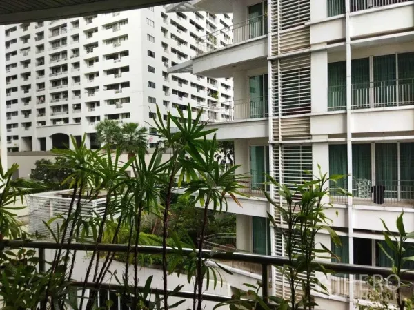 公寓 出租在Pathum Wan, Bangkok - 阳台视角，摆放盆栽，可见白色公寓楼与绿化景观。
