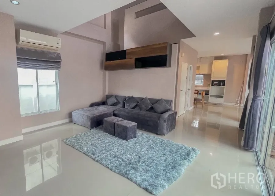 บ้านเดี่ยว for rent or sale in Saphan Sung, Bangkok - ห้องนั่งเล่นพร้อมโซฟาเข้ามุมสีเทา พรม และประตูกระจกบานเลื่อน.