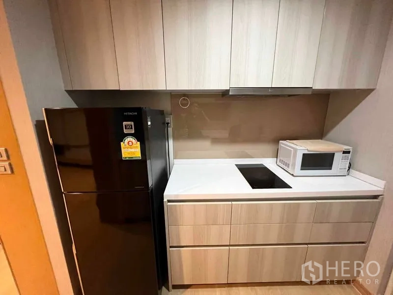 Condominium for rent or sale - Kitchen detail with cooktop, range hood, microwave, and refrigerator.