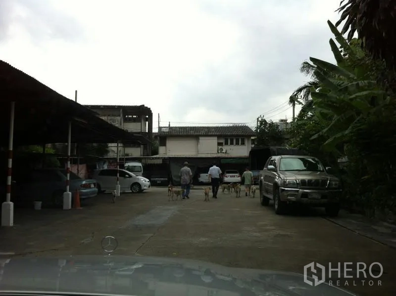 Factory for rent in Khlong San, Bangkok - Spacious parking yard with covered bays and vehicles at a Bangkok factory site.