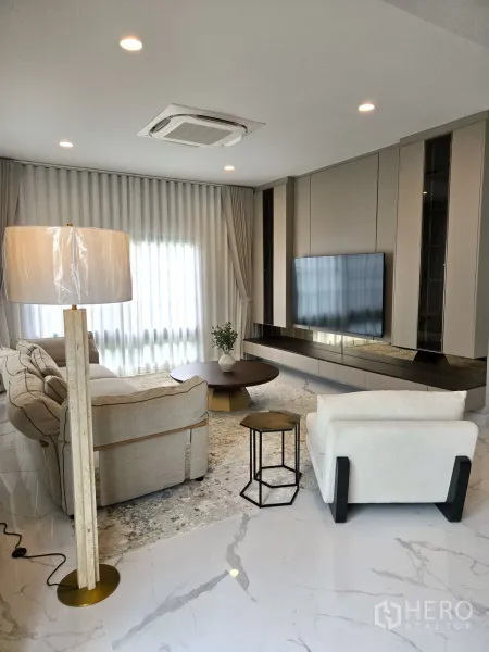 บ้าน ให้เช่าในBang Phli, Samut Prakan - ห้องนั่งเล่นชั้นล่าง โซฟาชุดใหญ่ ผนังทีวี และผ้าม่านทึบโปร่ง