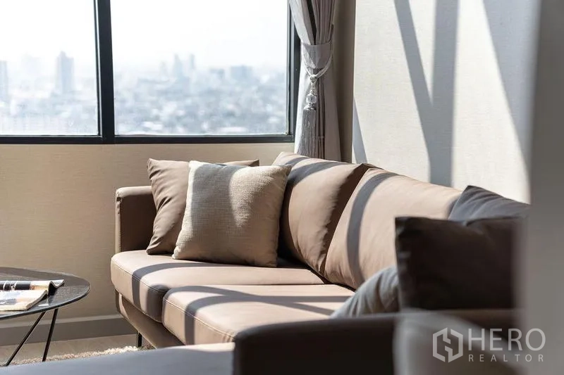 公寓 出租在Sathon, Bangkok - 沙发与抱枕贴近观景窗的特写，可见城市美景。
