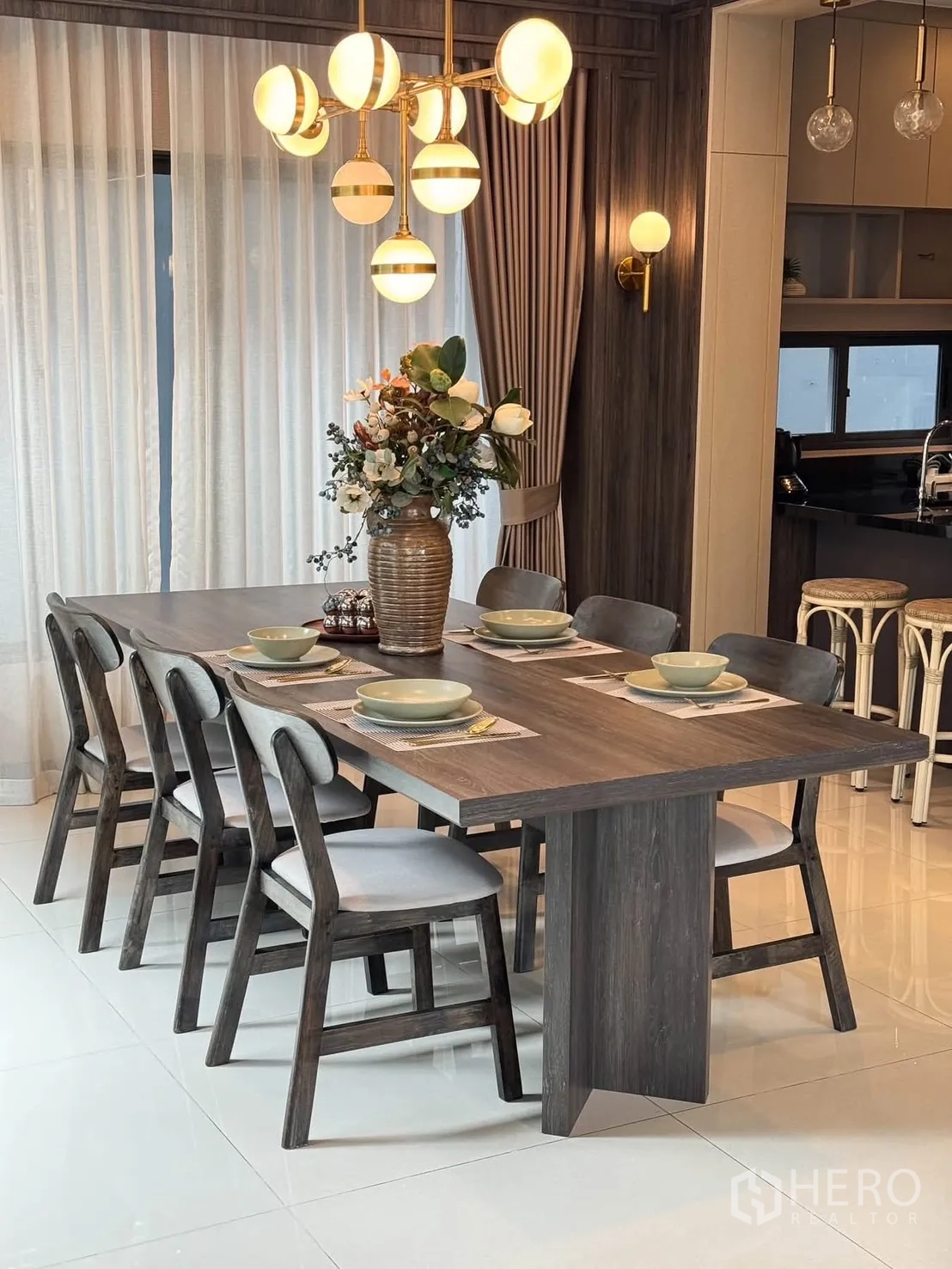 Detached House for rent in Bang Kapi, Bangkok - Dining table set for six under a modern globe chandelier beside sheer curtains.