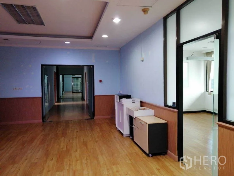 办公空间 出租在Bueng Kum, Bangkok - 开放办公区配打印设备，走廊两侧为玻璃框办公间和筒灯。