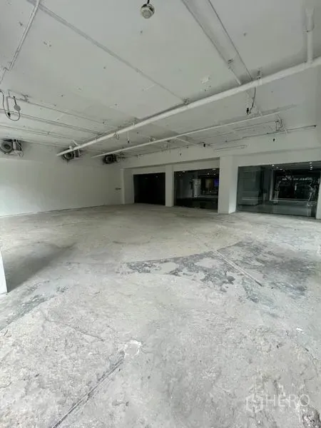 零售空间 出租在Watthana, Bangkok - 宽敞白盒子空间，外露天花管线、水泥地面与转角玻璃窗。