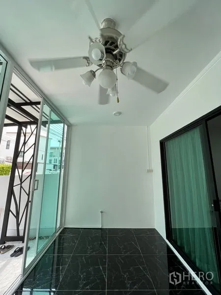 Townhouse for sale in Bang Kapi, Bangkok - Front sunroom with ceiling fan and black marble-look floor tiles.